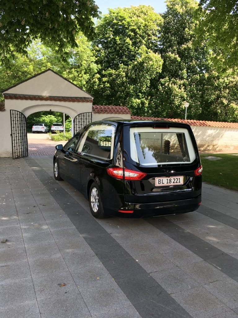 Sort rustvogn foran kirkegård i Danmark
